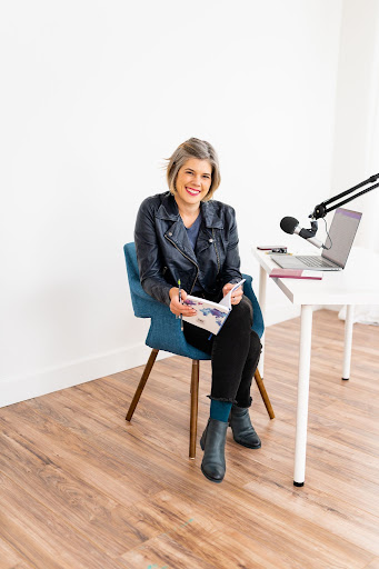 Brigette smiling while sitting at desk with laptop and mircophone.